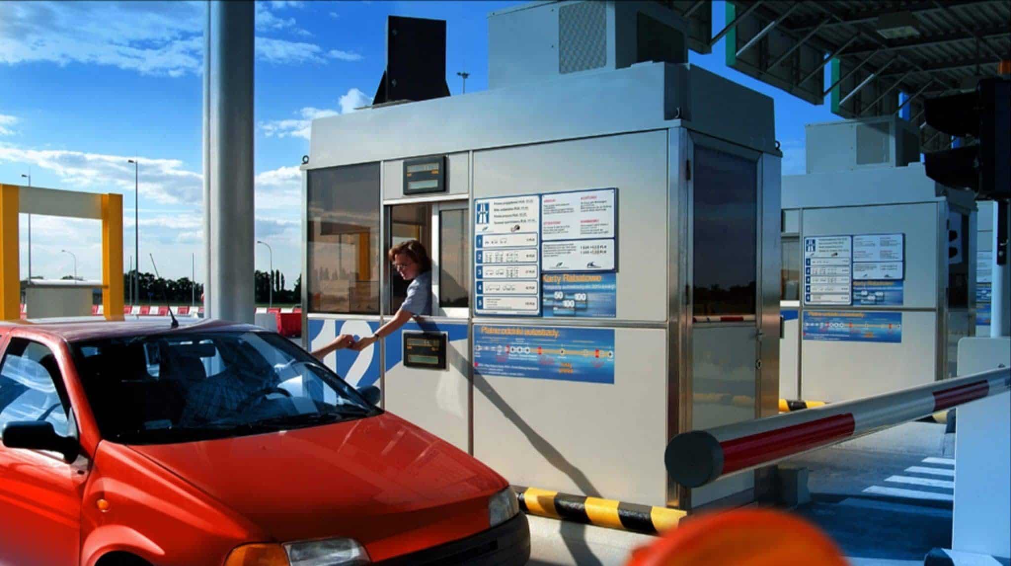 Woman in toll booth serving man in red car